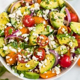 A white bowl full of avocado tomato salad