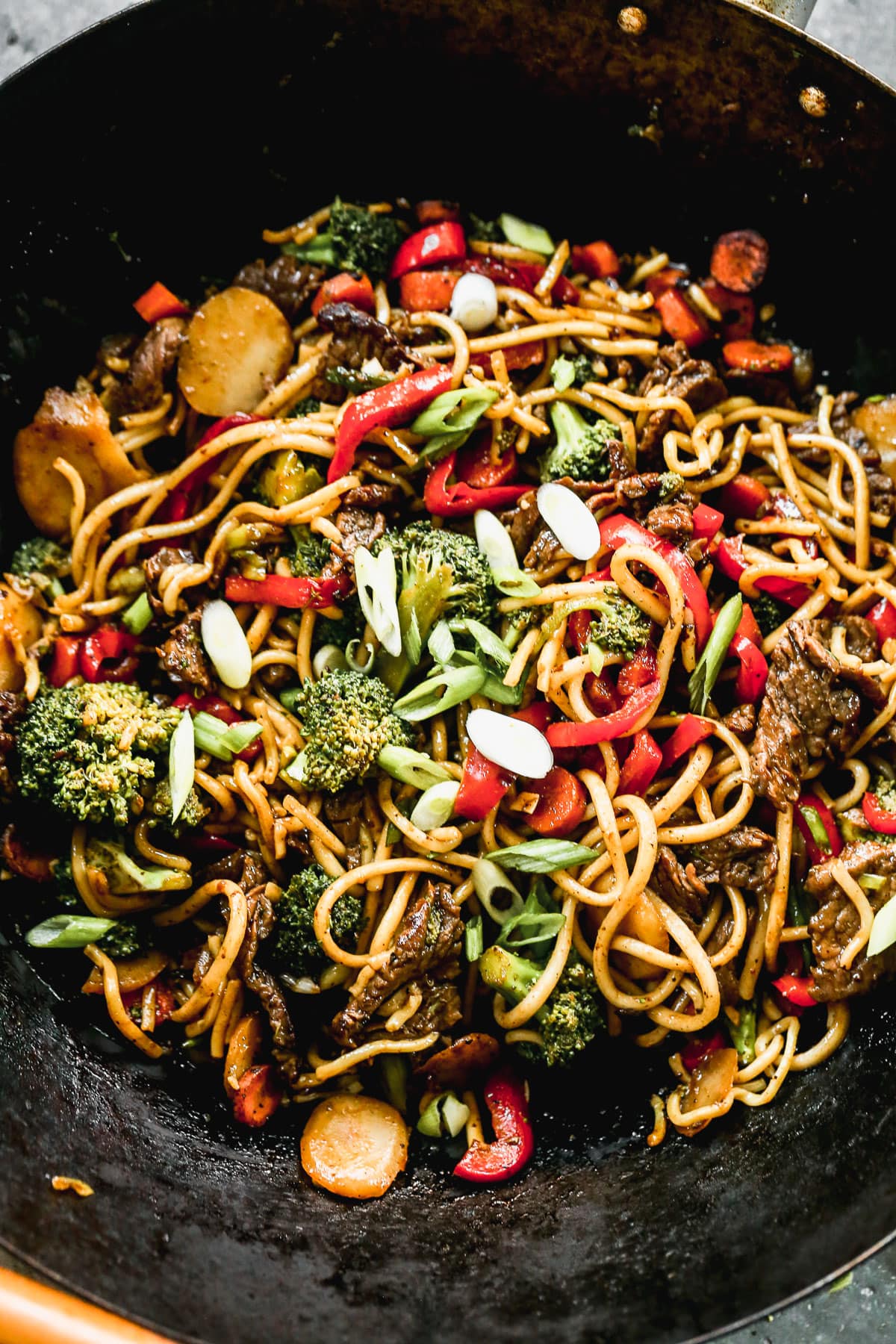 beef lo mein and vegetables cooking in skillet