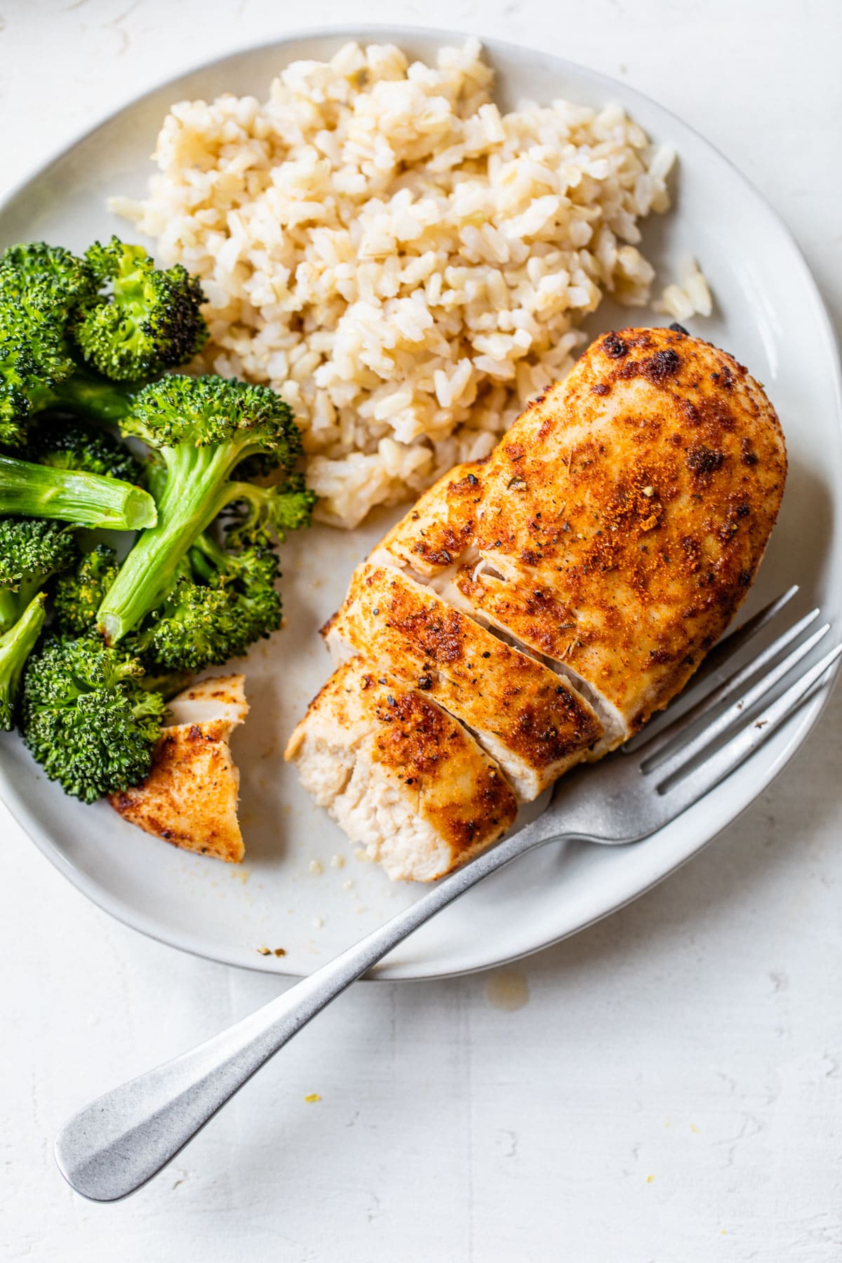 Air fryer chicken breast on a plate with broccoli and rice