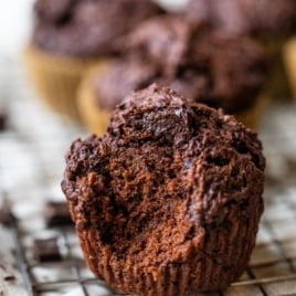A wire rack with moist chocolate muffins filled and topped with chocolate chunks