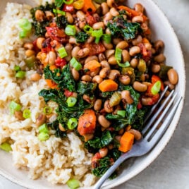 a bowl of vegetarian hoppin' john without meat with fork and green onions on side