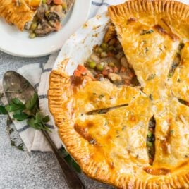 A vegetarian pot pie made with white beans and mushrooms and vegetables in a white pie dish