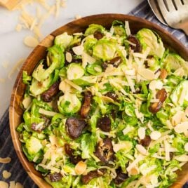 Fresh and healthy brussels sprouts slaw made with shredded brussels sprouts in a honey lemon Dijon dressing, inside of a wood bowl