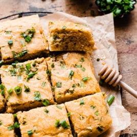 Slices of cheesy jalapeno cornbread with honey on parchment paper