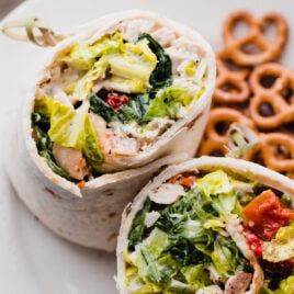 Chicken Caesar wraps on a plate with pretzels
