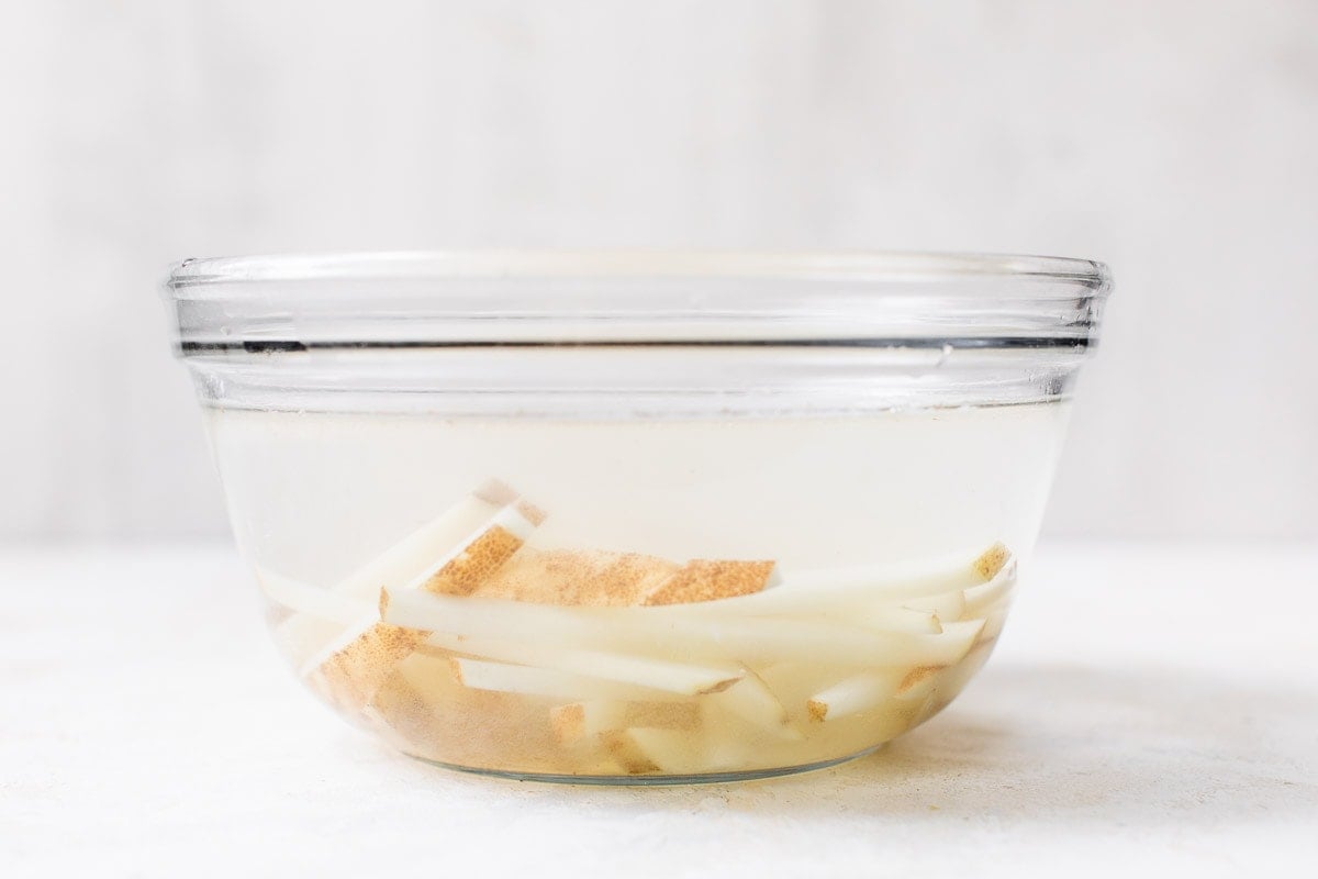 Sliced potatoes in a bowl of water