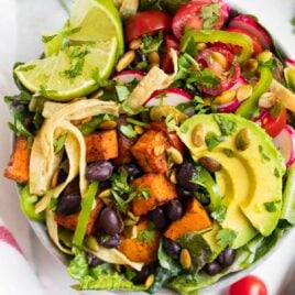 A healthy Mexican salad bowl with lettuce, beans, tomatoes, avocado and tortilla strips