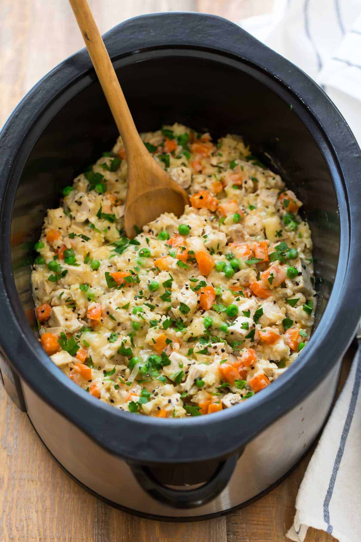 A slow cooker filled with a cheesy casserole