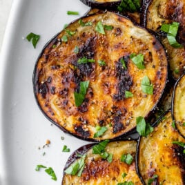 grilled eggplant medallions on a plate with oil and seasoning