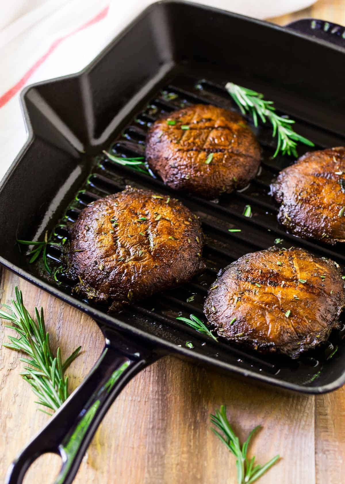 Grilled portobello mushrooms on a grill pan with fresh herbs