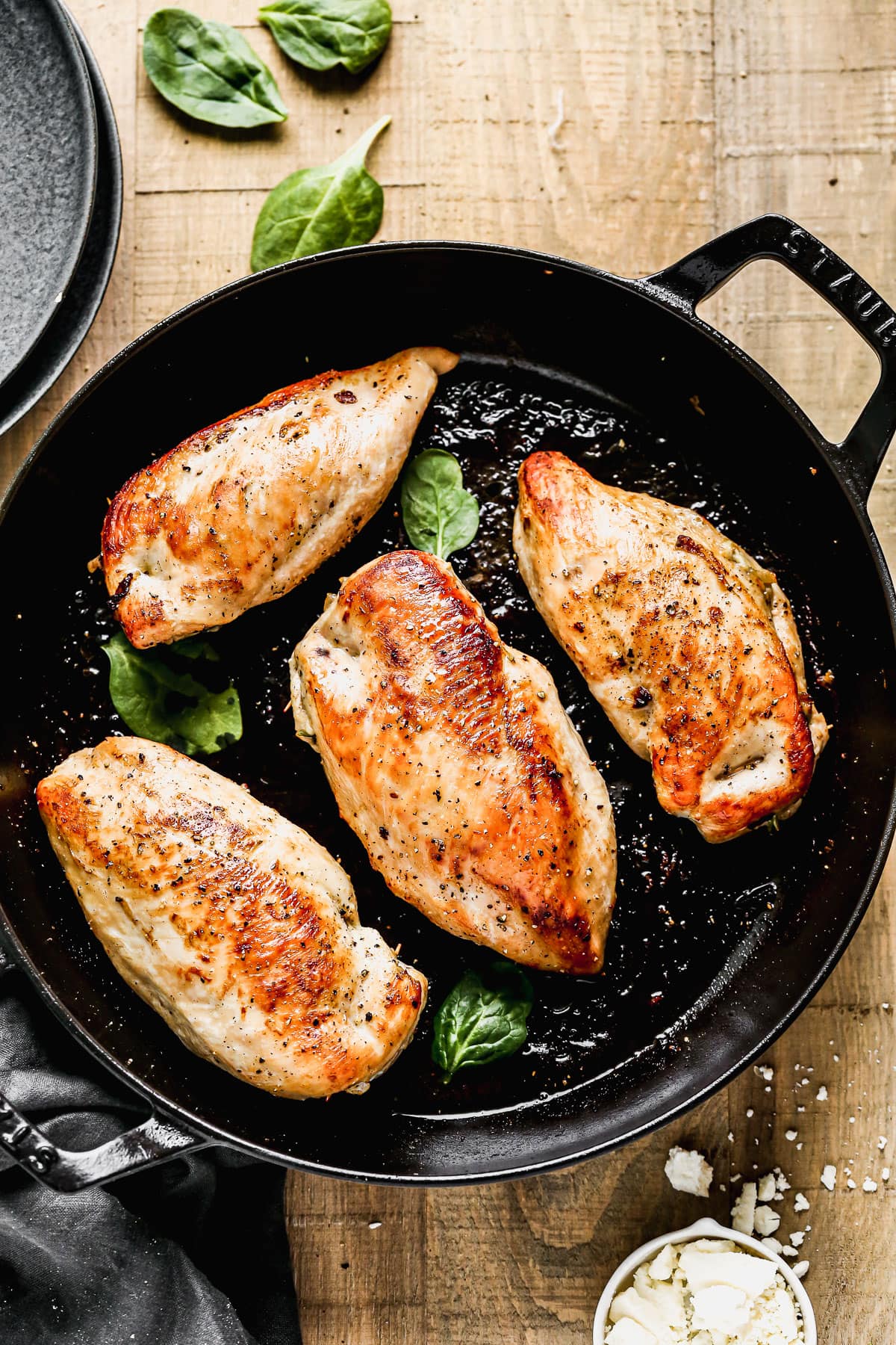 Four spinach stuffed chicken breasts in a skillet