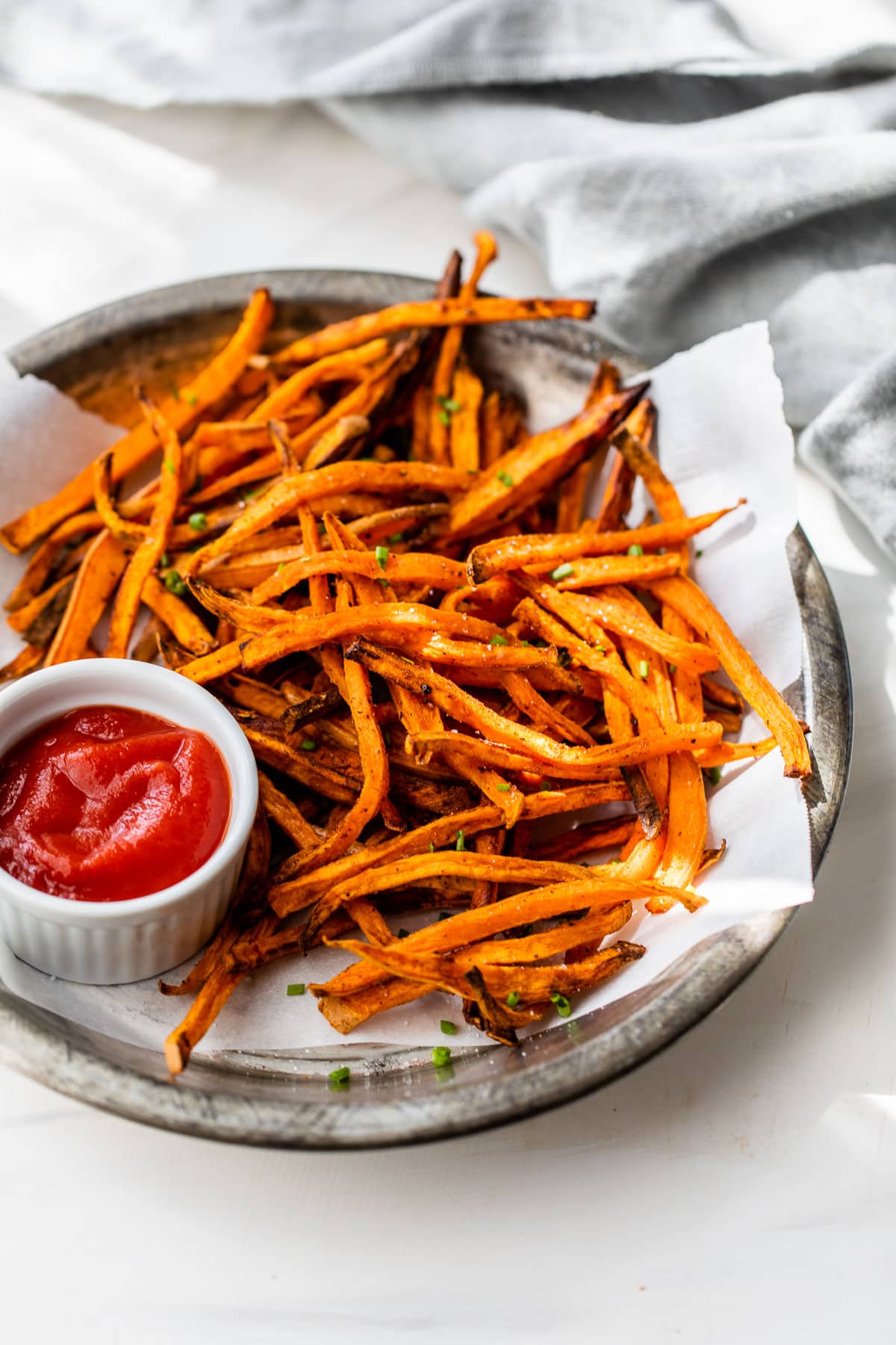 crispy air fryer sweet potato fries on a plate with small bowl of ketchup