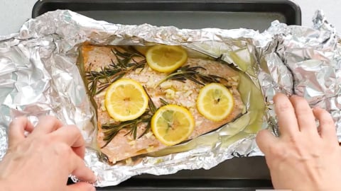 folding foil around garlic salmon with lemon for baking