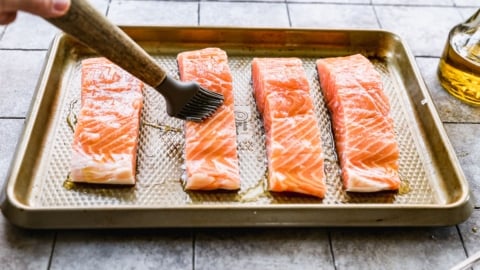 brushing salmon for grilling on a baking sheet