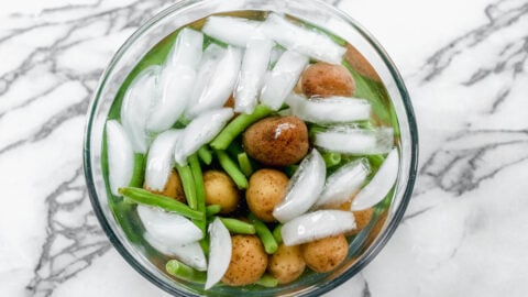 A bowl of ice water with potatoes and green beans