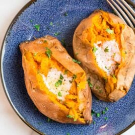 Two sweet potatoes with butter on a blue plate