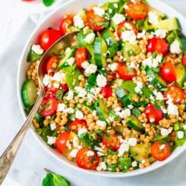bowl of Israeli pearl couscous salad with a serving spoon in it