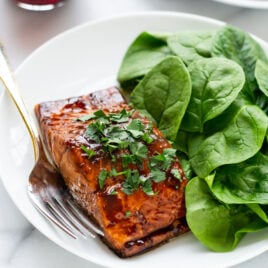 white dinner plate with Balsamic Glazed Salmon and fresh spinach