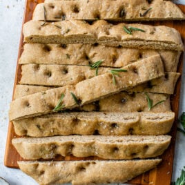 no knead focaccia sliced on a cutting board with sea salt and rosemary