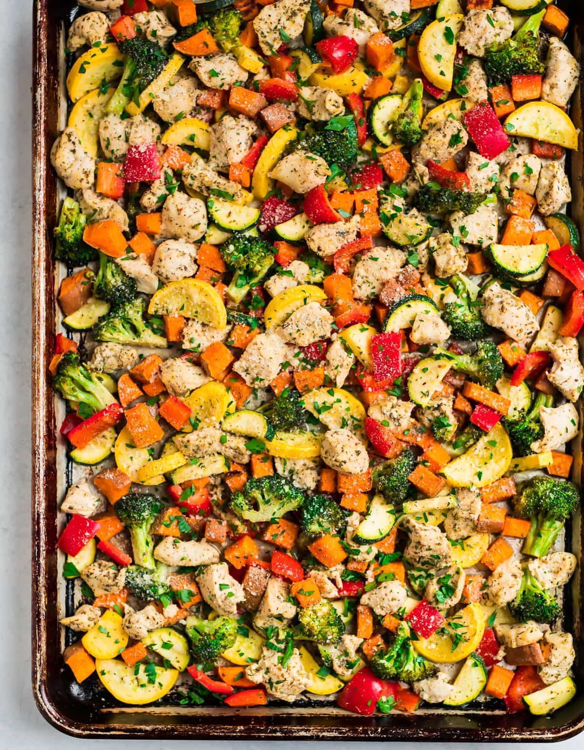 Oven baked Sheet Pan Chicken with Broccoli, Sweet Potatoes, and Zucchini and a lemon garlic Parmesan topping.