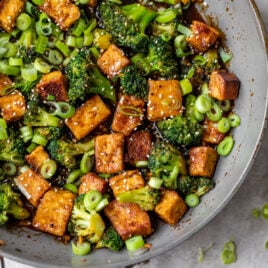 A wok with tofu, broccoli, and green onions